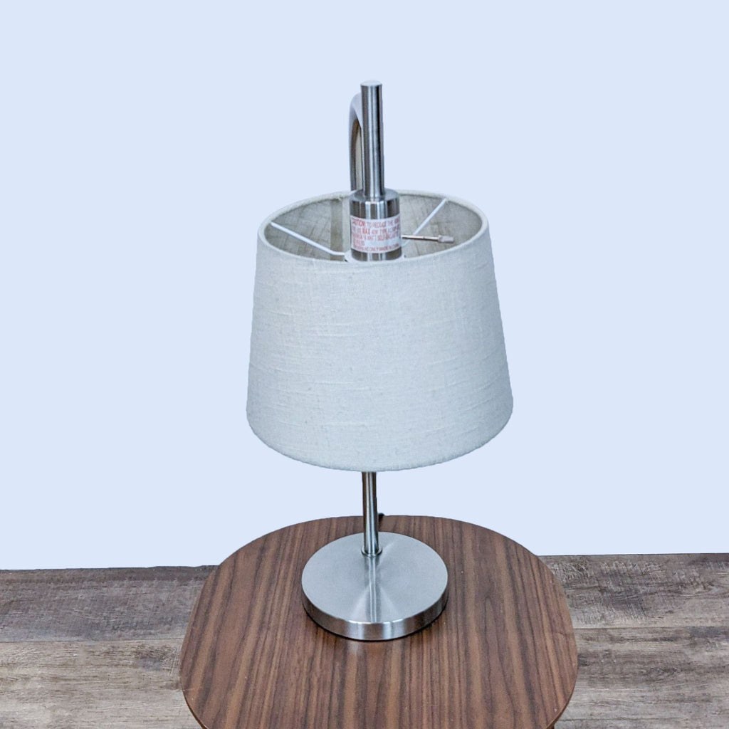 Side view of Reperch lamp with a modern design and clean white shade on a table.