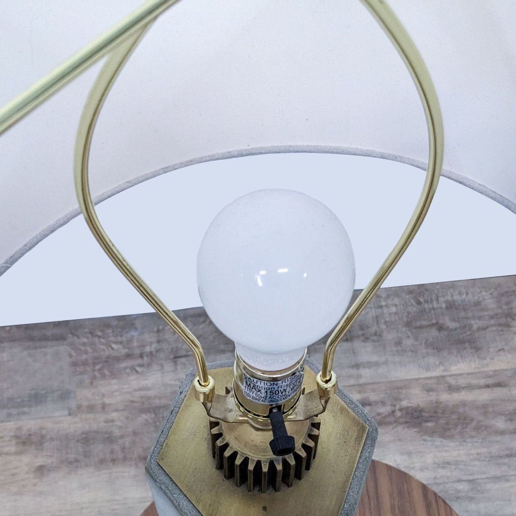Close-up of a Reperch lamp bulb and brass fittings against a wooden surface.