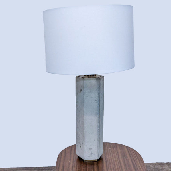 White lampshade with textured concrete base on a wooden table, by Reperch.