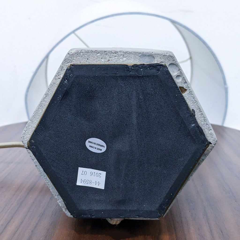 Hexagonal base of a Reperch lamp, showing texture and label details on a wooden table.