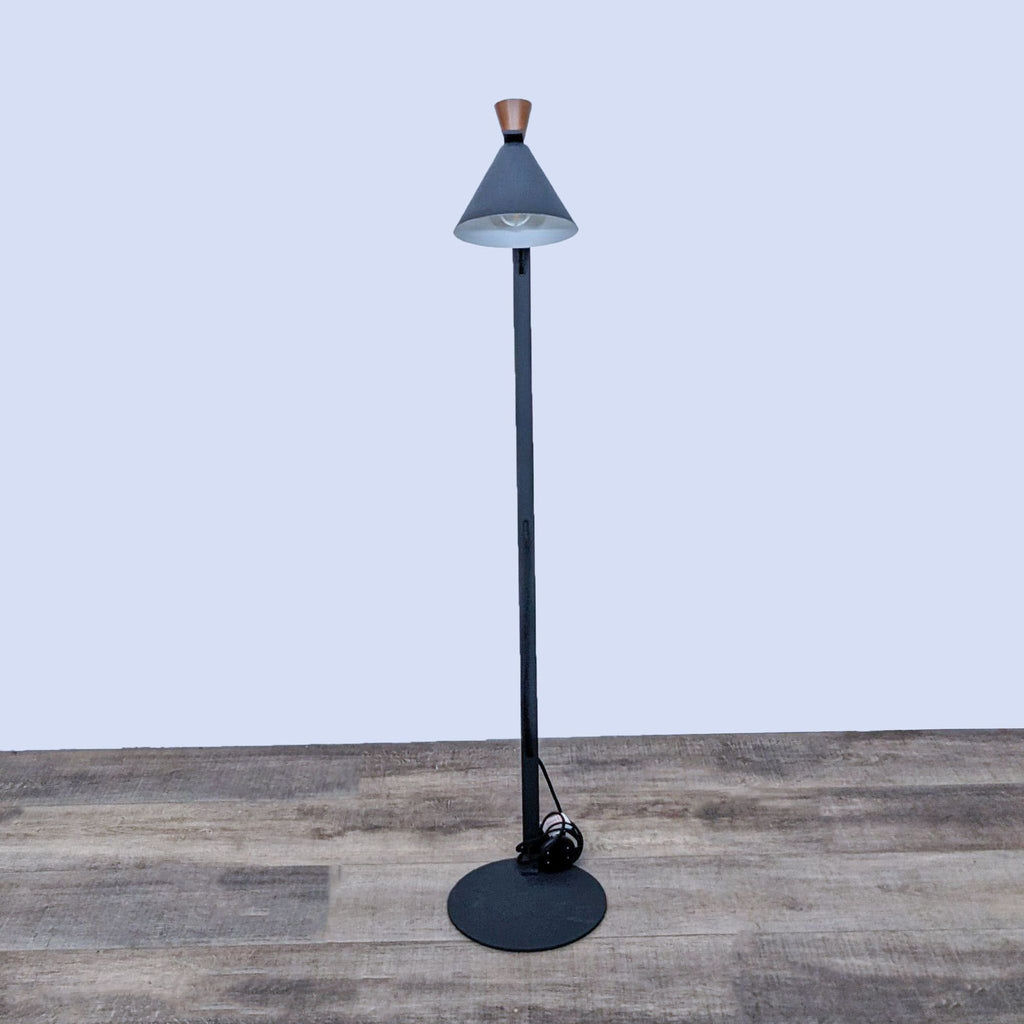 Minimalist black floor lamp by Reperch, featuring a cone shade and circular base, on wooden flooring.