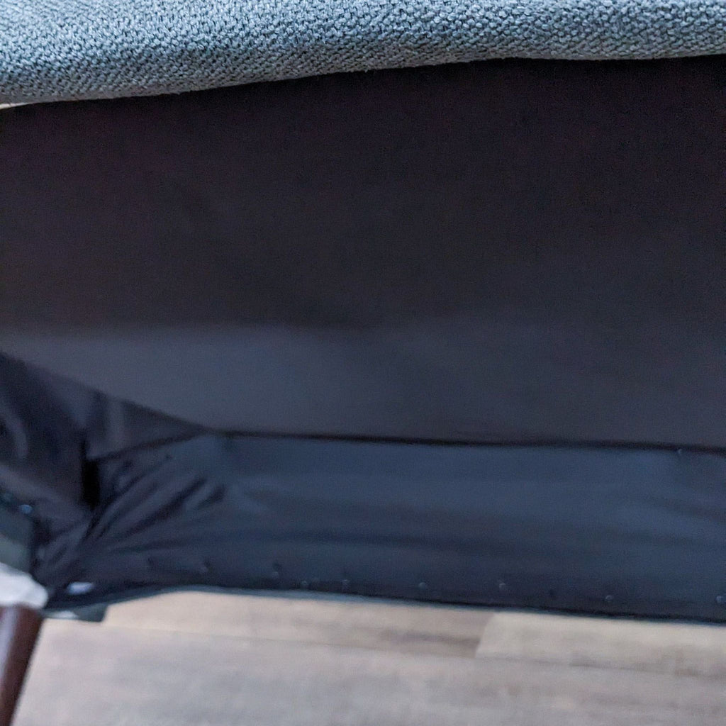 Close-up of the bottom detailing of a sofa with a dark finish.