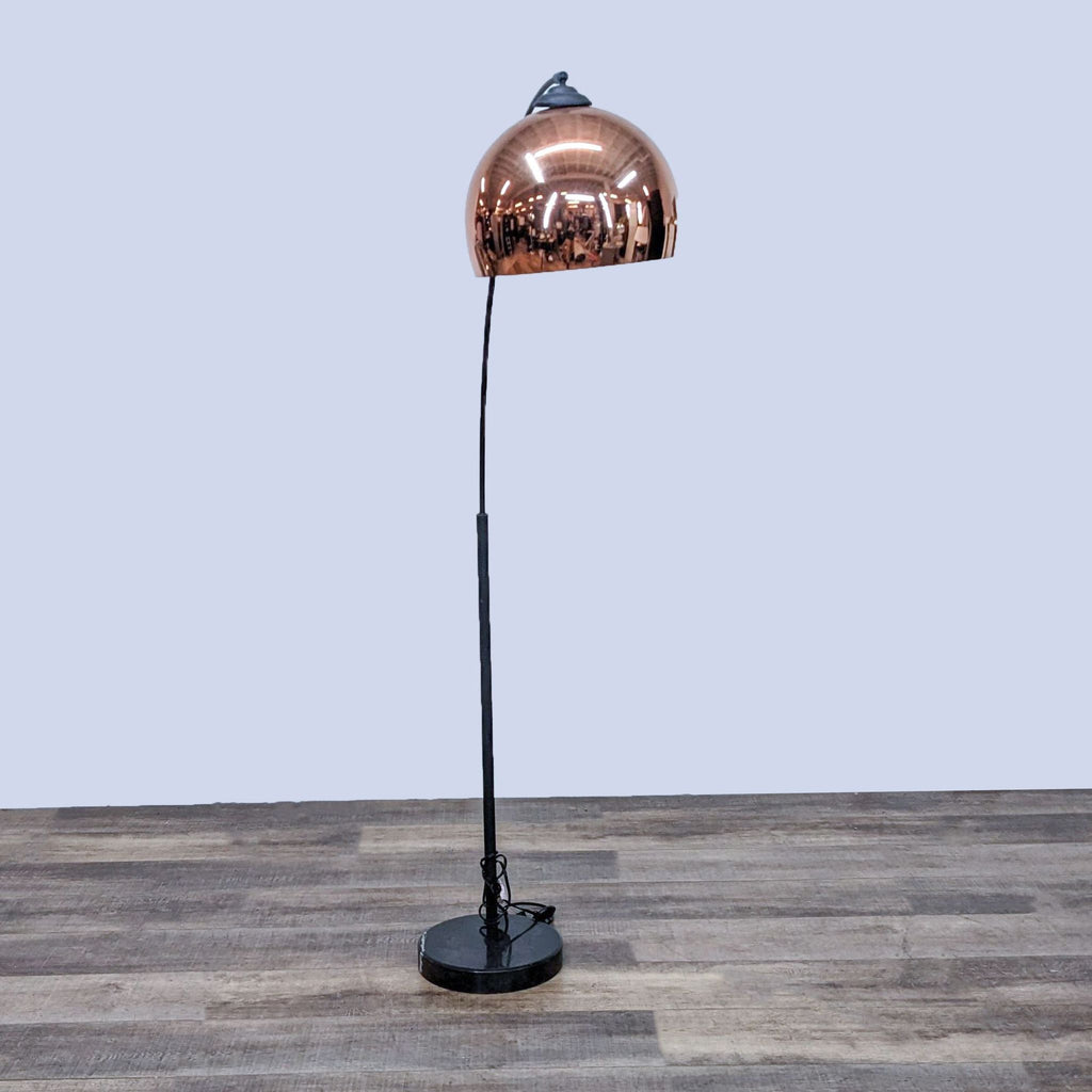 Reperch lamp featuring a sleek black base and curved copper shade, set on a textured floor.