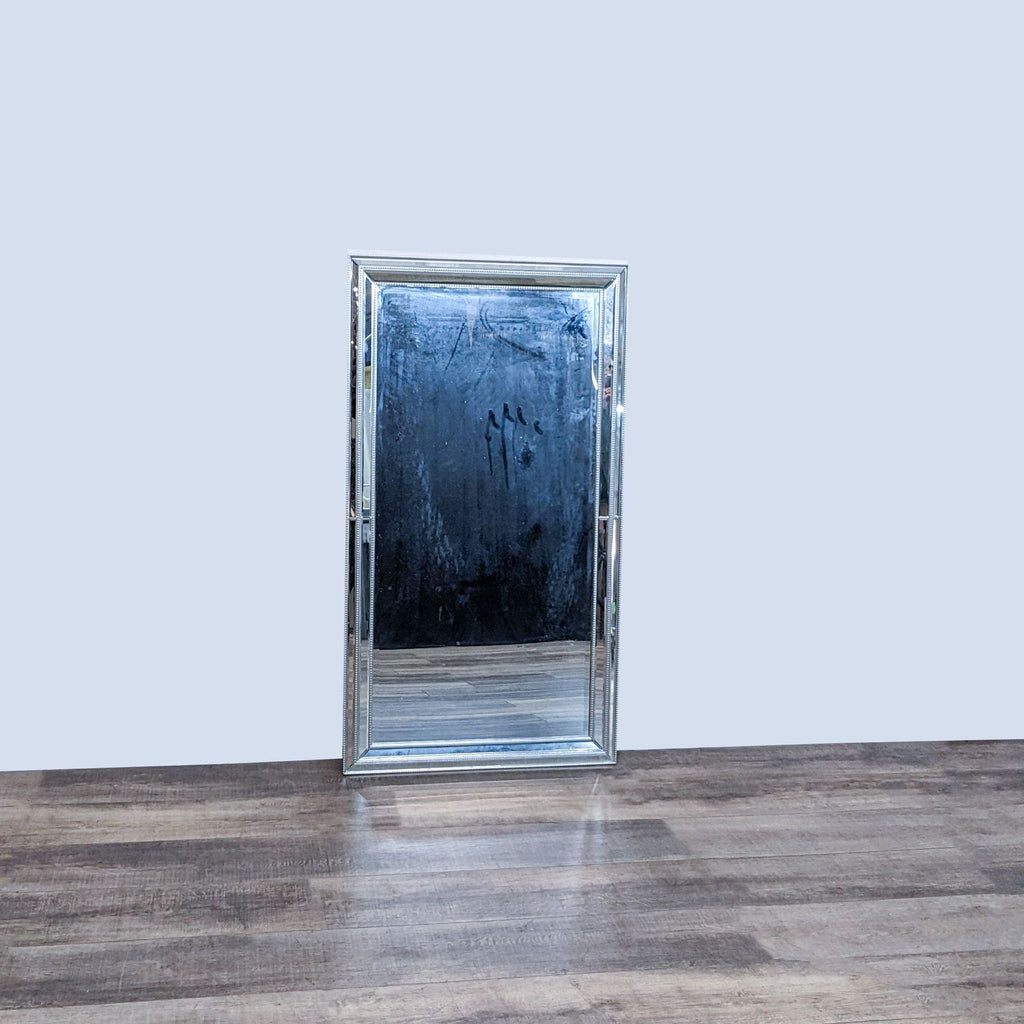 Stylish BP Industries wall mirror showing a beveled glass with silver beaded trim detailing on a wood floor.