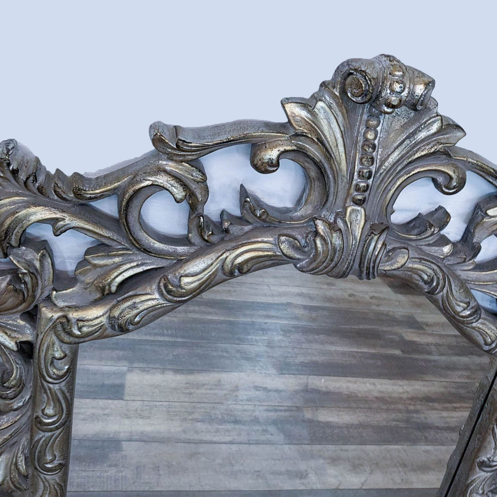 Close-up of ornate mirror frame with intricate silver and gold detailing.