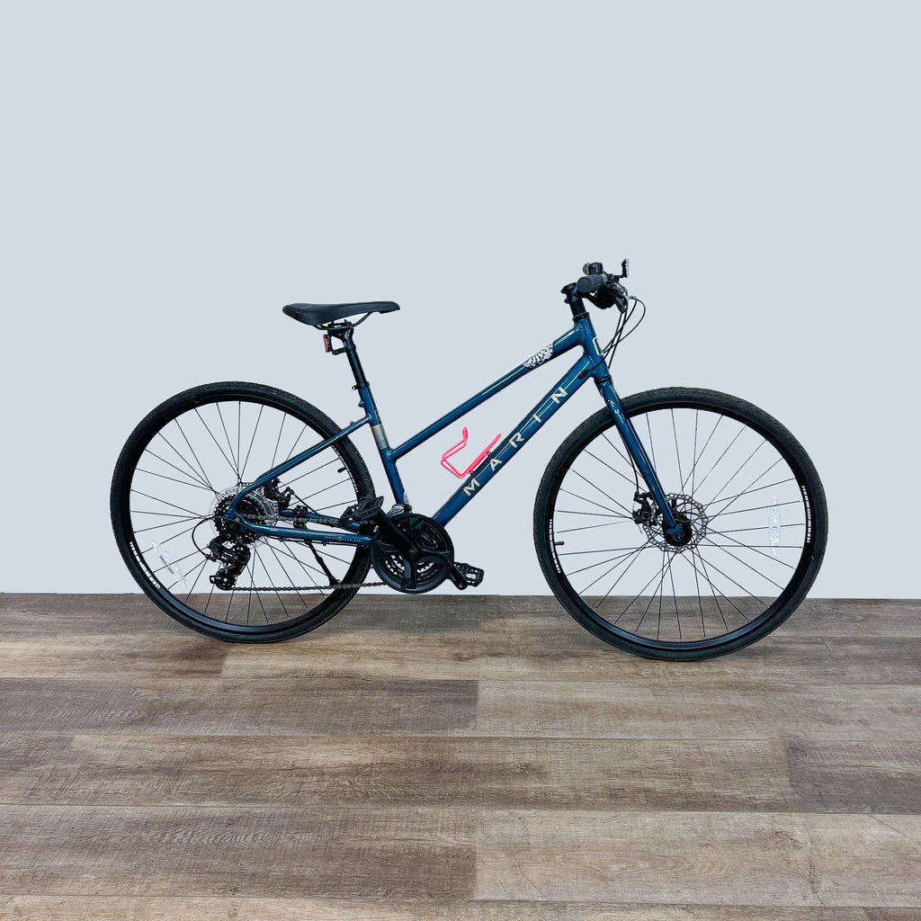 Blue Marin hybrid bike on wooden floor, side view showcasing the brand logo.
