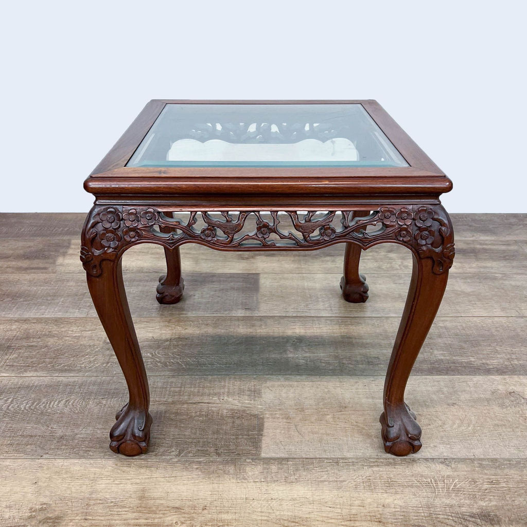 Chinese Chippendale table with ball and claw feet, wood framing, and glass top.