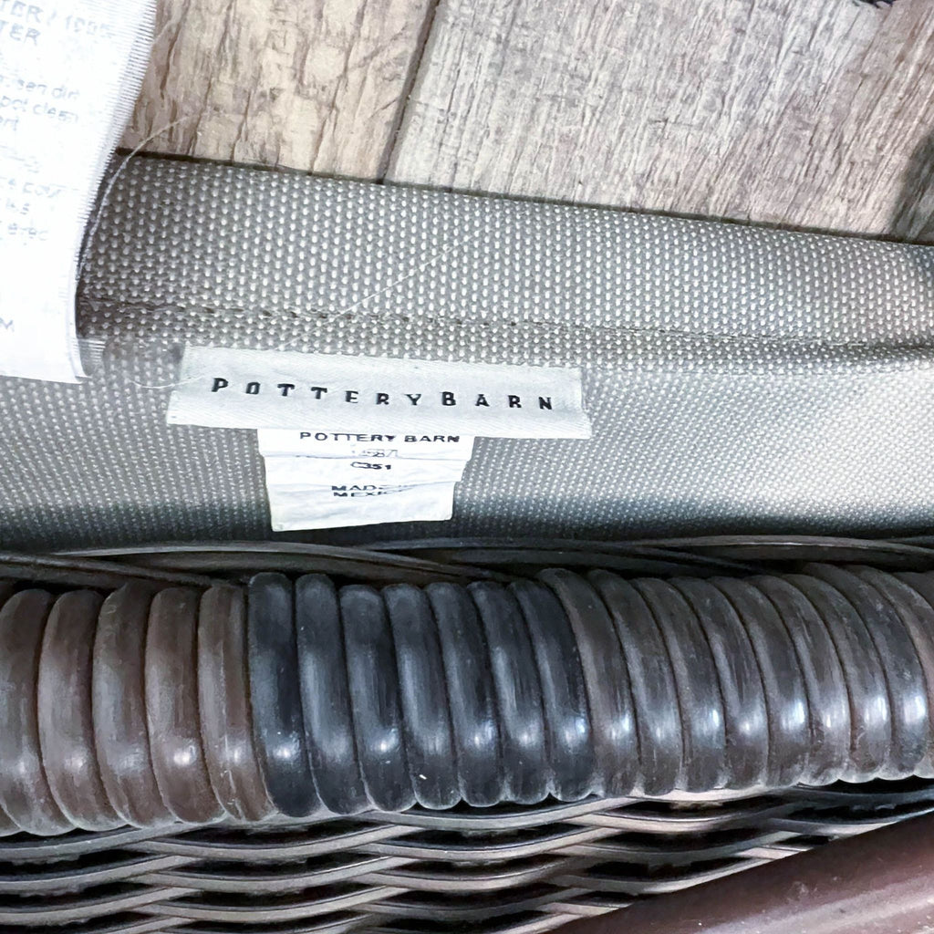 Close-up of Pottery Barn label on wicker chaise with protective cover.