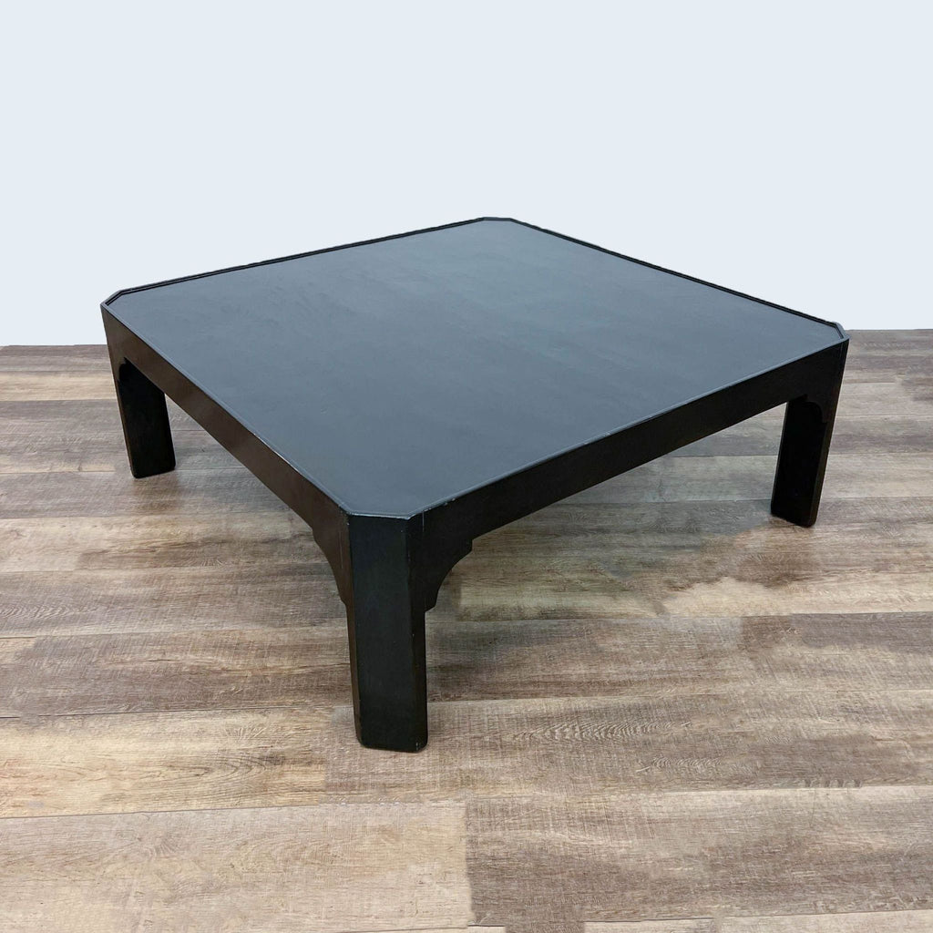 Stylish Dennis & Leen coffee table, black finish, set against a wooden floor background.