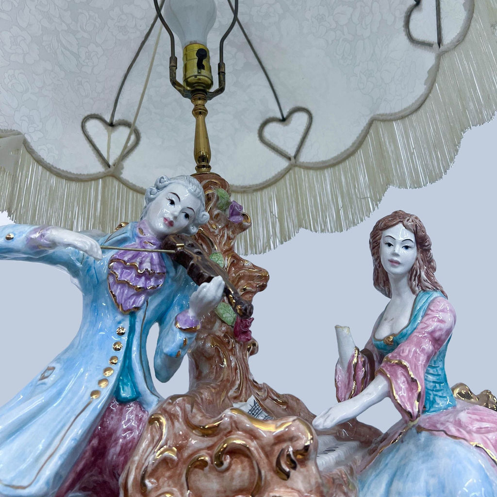 Close-up of porcelain musicians under a decorative lamp shade with hearts.  