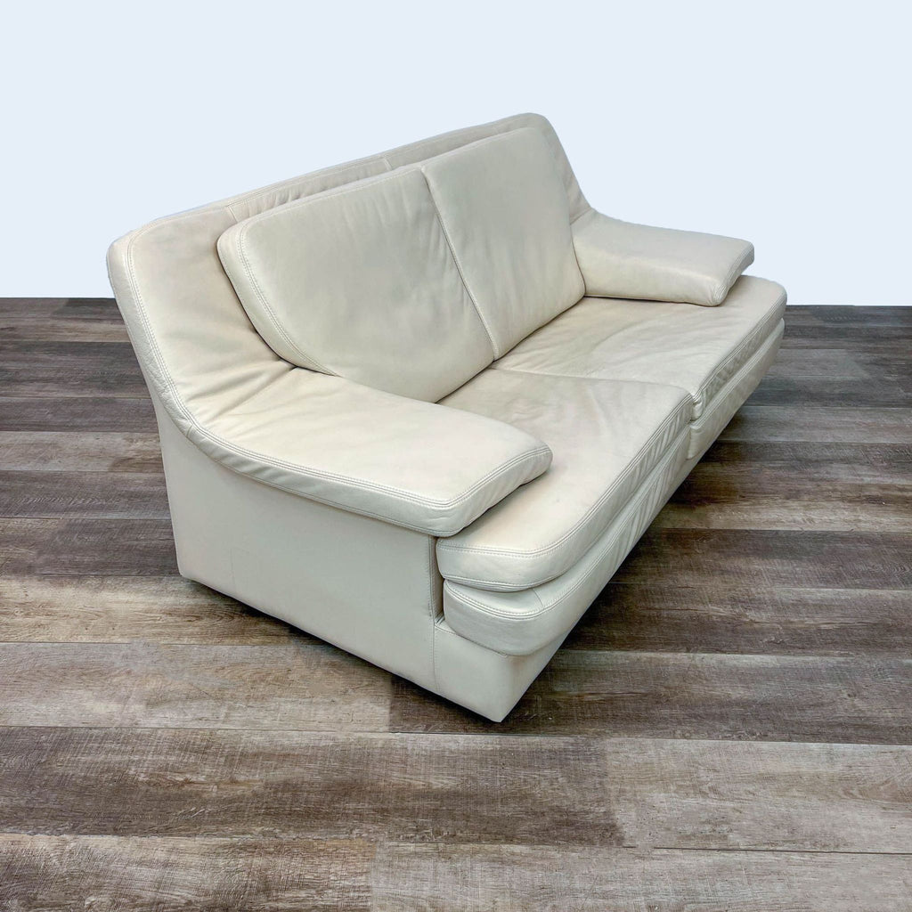 Curved-back loveseat featuring ivory leather and supportive arms.