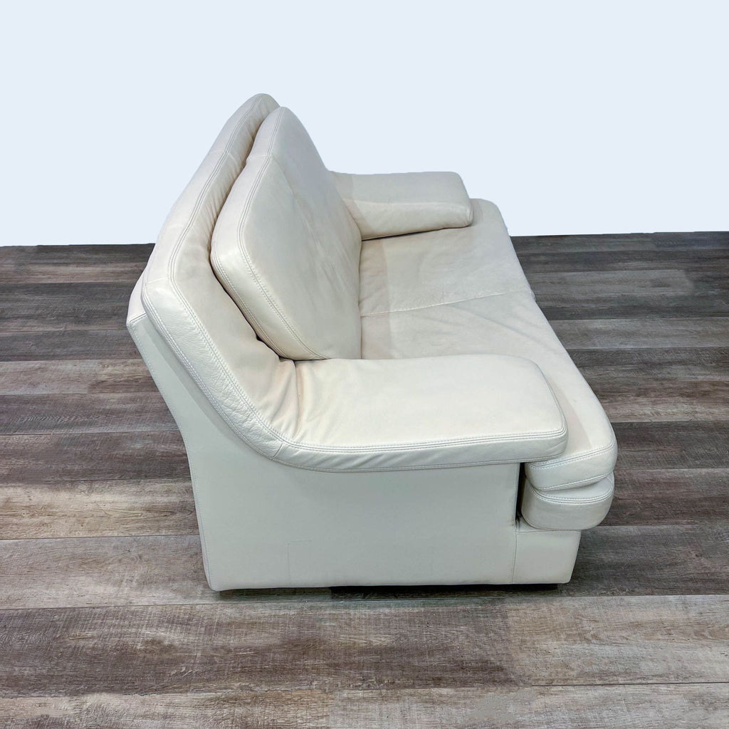 Side view of ivory leather loveseat with plush cushions.