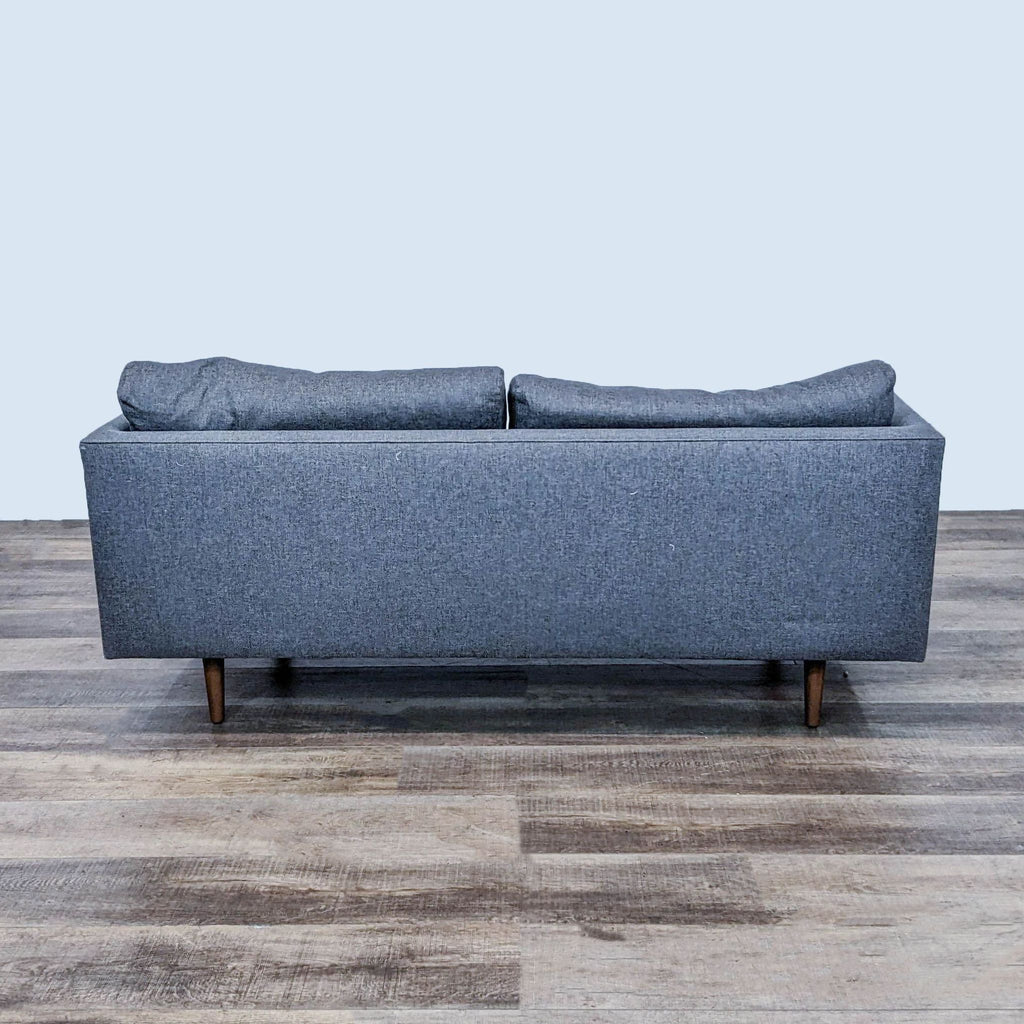 Back view of a gray loveseat with clean lines and tapered wooden feet.