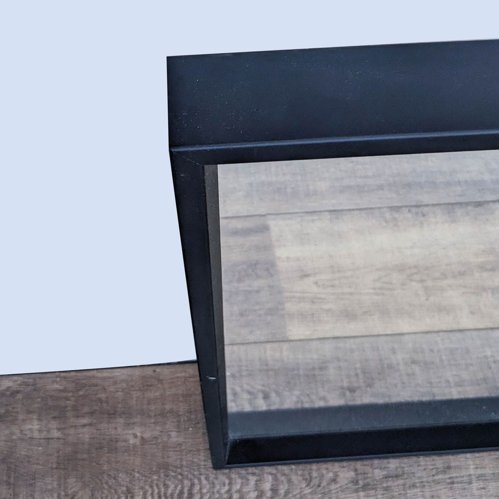 Close-up of the black frame of the wall mirror, showing details.