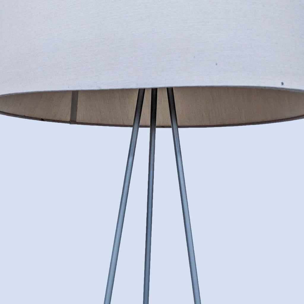 Detailed view of the lamp’s fabric shade and metal tripod stand.