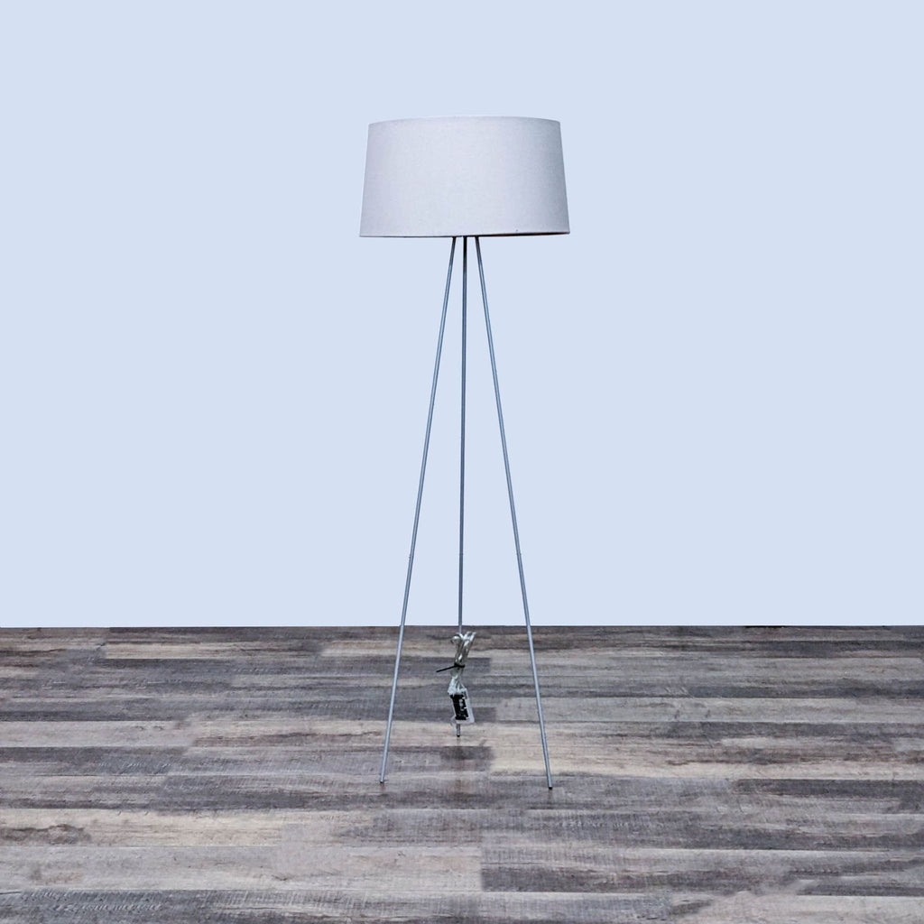 Mid-century style lamp with three slender legs and a fabric shade.