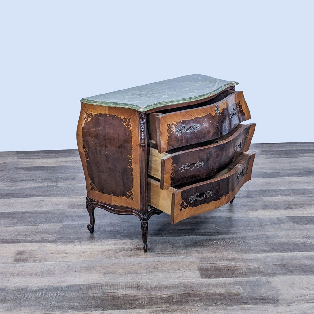 Side view of open Louis XV chest with ornate carvings and green marble top.
