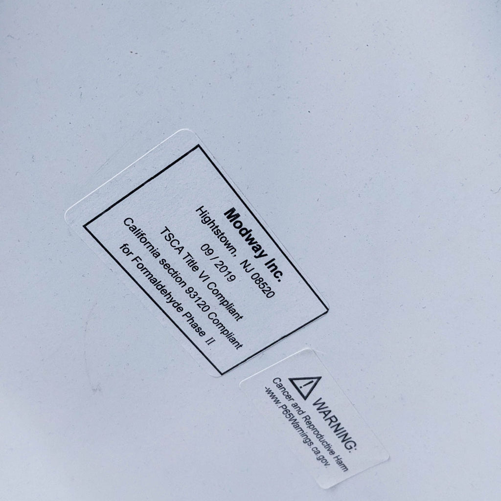 Close-up of a label for a Modway table indicating compliance with safety standards.