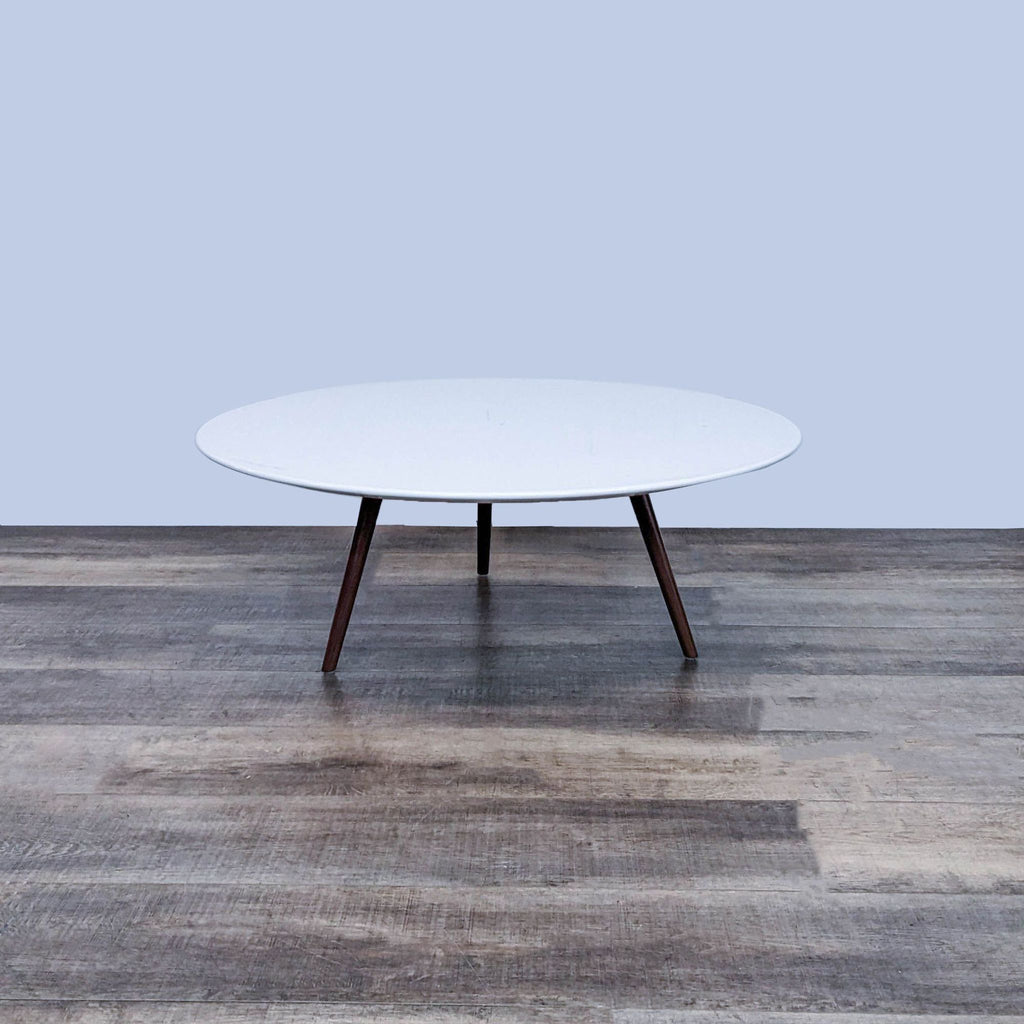 Modway coffee table featuring a white round top and wood dowel legs, set on a wooden floor.