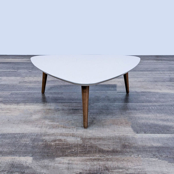Triangular white coffee table with sleek wooden legs from Reperch.