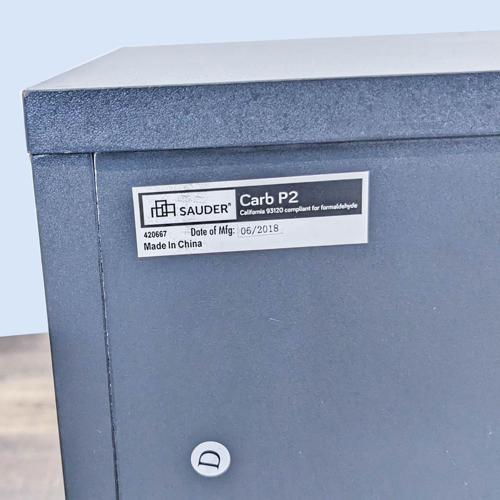 Close-up of Sauder label on entertainment center, showing compliance info.