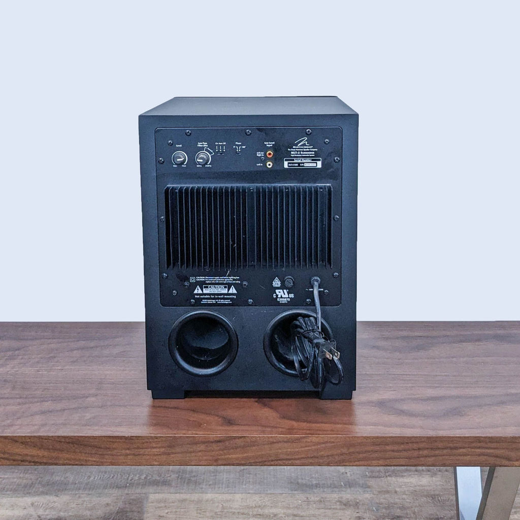 Rear panel of a Martin Logan subwoofer showing controls and ports on a wooden table.