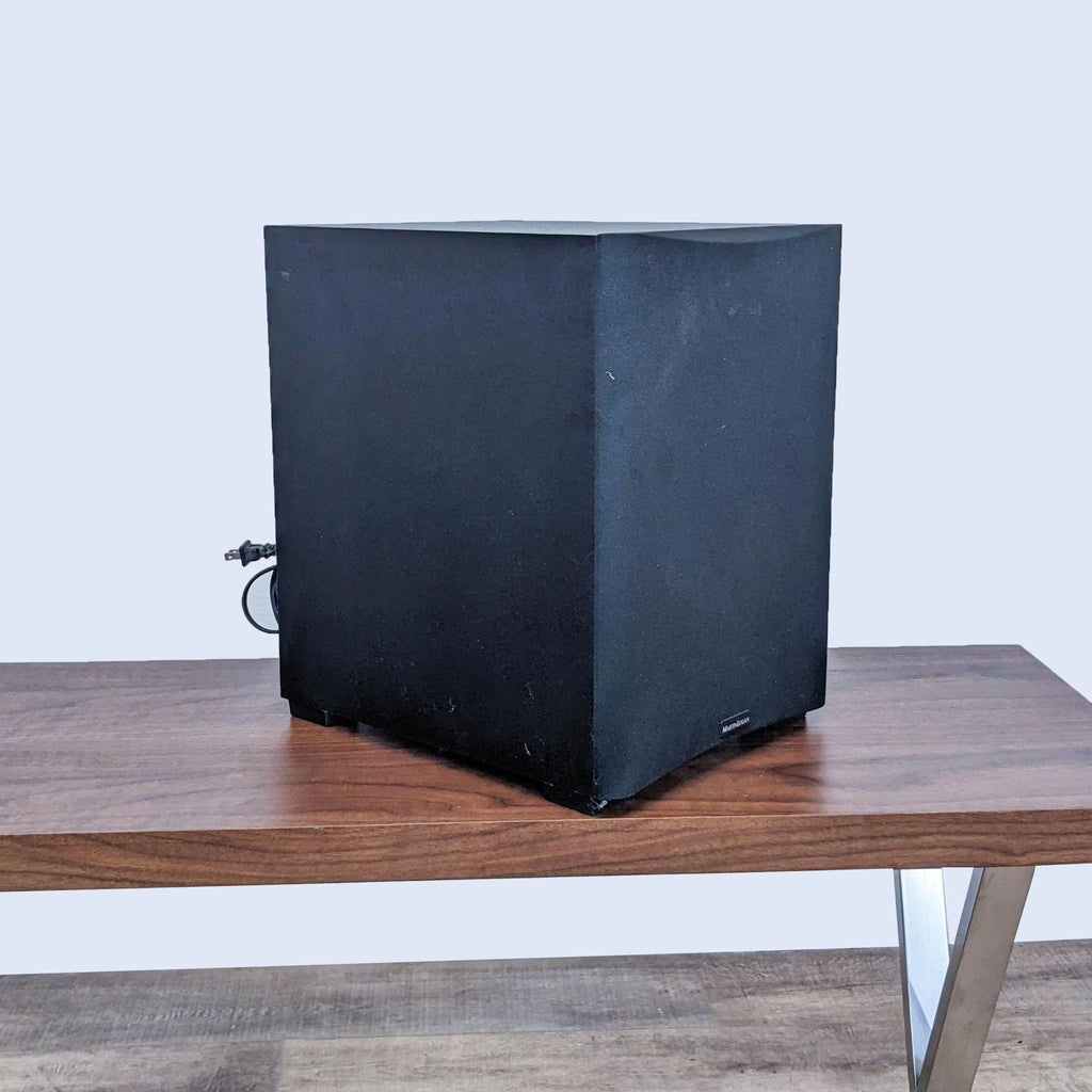 Side view of a Martin Logan subwoofer with visible wiring on a wooden table.  