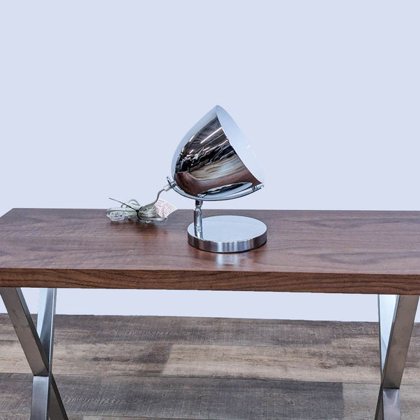 Chrome spotlight lamp on a wooden table by Zuo Modern.