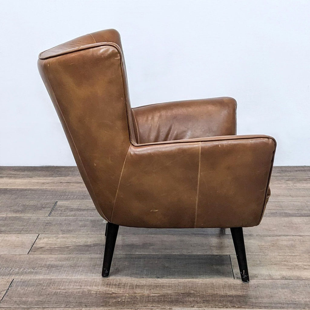 Side view of a brown faux leather side chair showcasing modern clean design on wooden flooring.