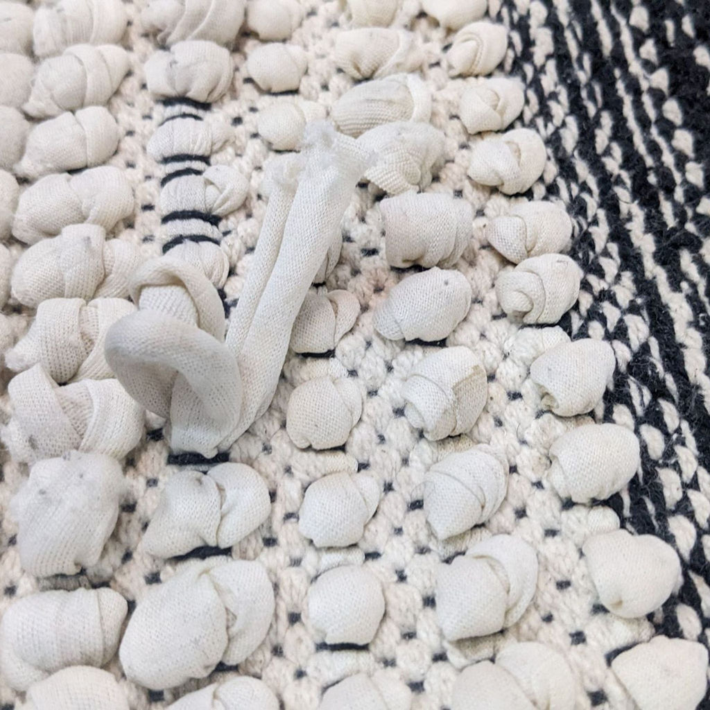 Detailed view of textured knots on an ivory and black rug.