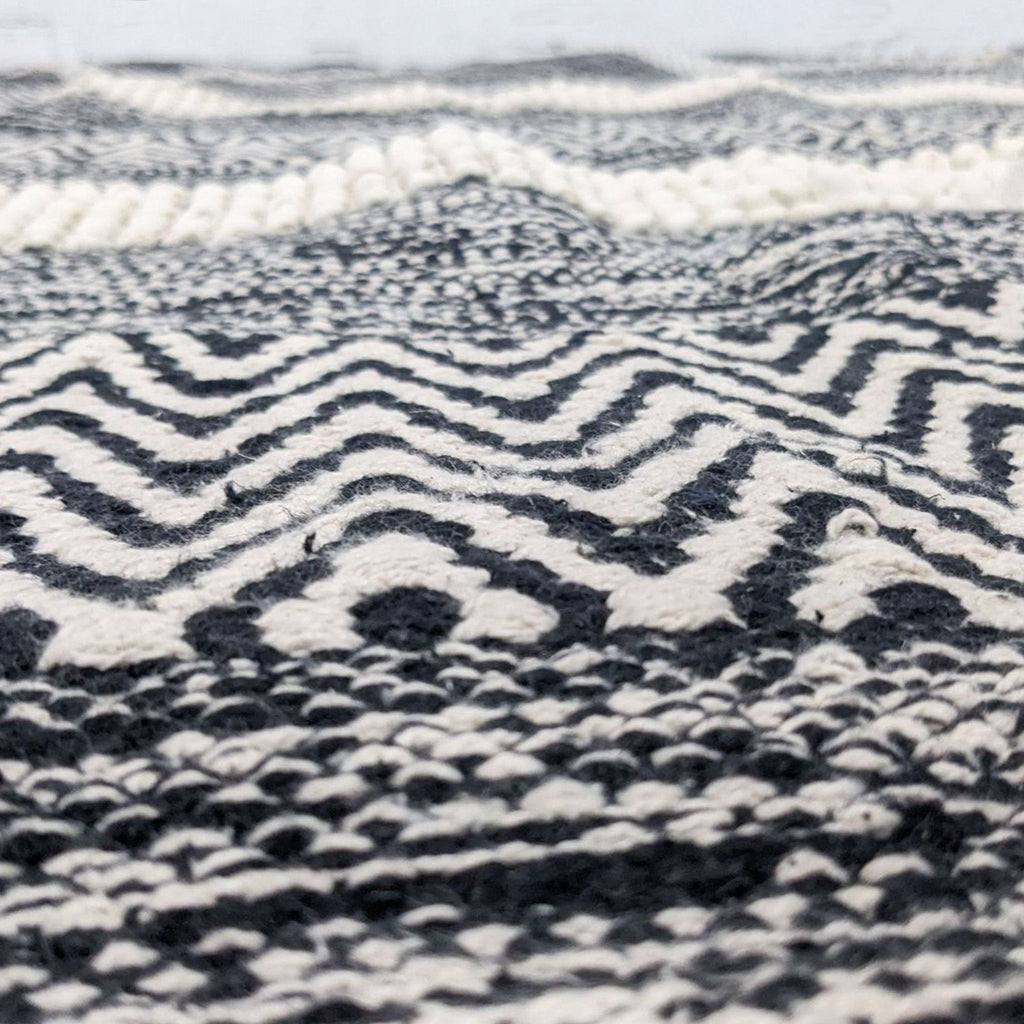 Close-up of textured patterns on a black and ivory area rug.