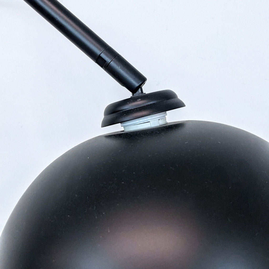 Close-up of Reperch lamp's black dome-shaped shade and adjustable arm joint.
