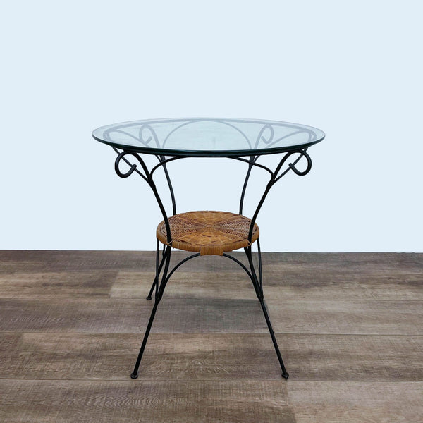 Glass bistro table with metal frame and wicker accent, viewed from the side.