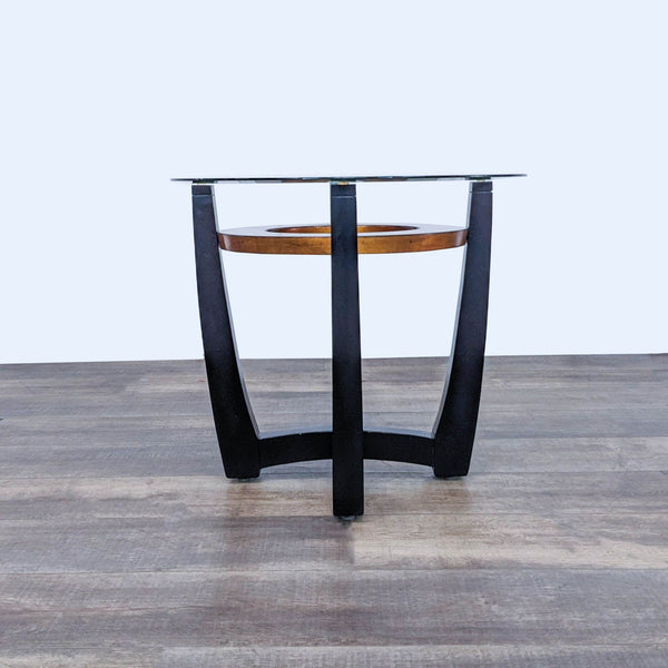 Reperch end table with a circular glass top and wooden base on dark legs.