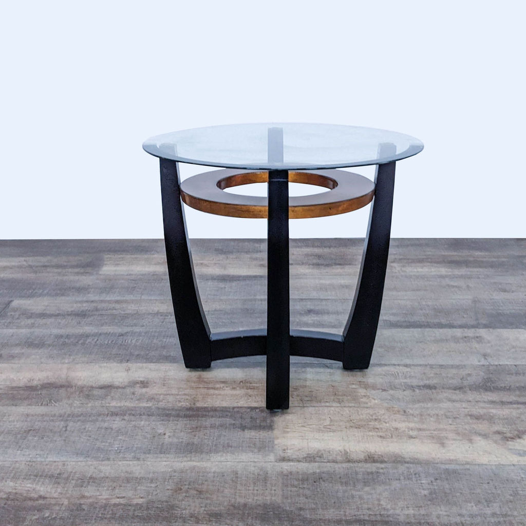 Round glass-top table by Reperch, featuring a wooden support and black curved legs.