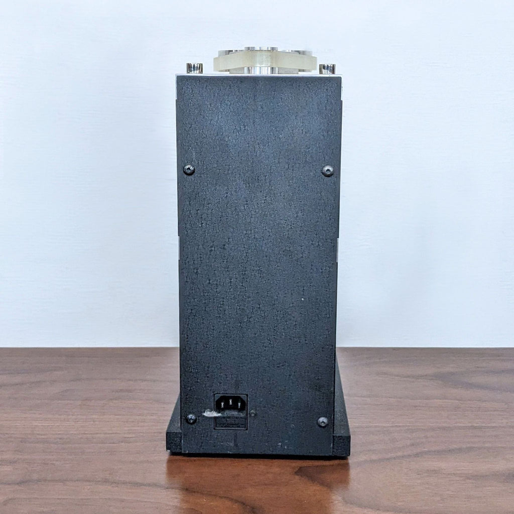 Back of a black machine on wood, showing a power socket.