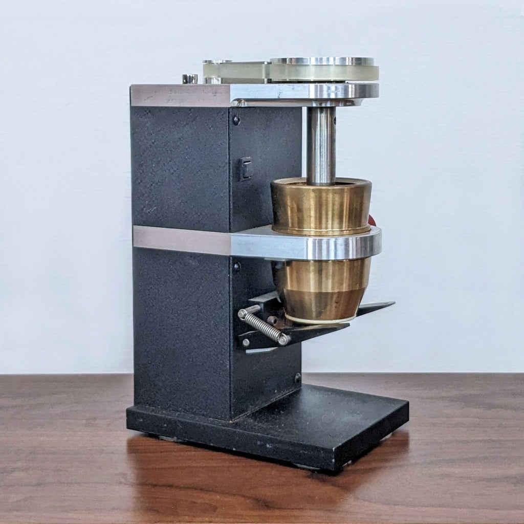 Side view of a black and brass device on a wooden surface.