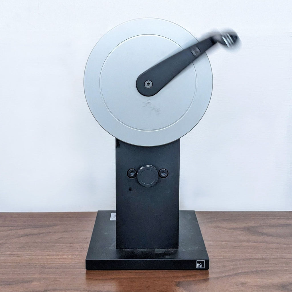 3. Circular crank-operated machine on a black base, with a minimalist modern design.