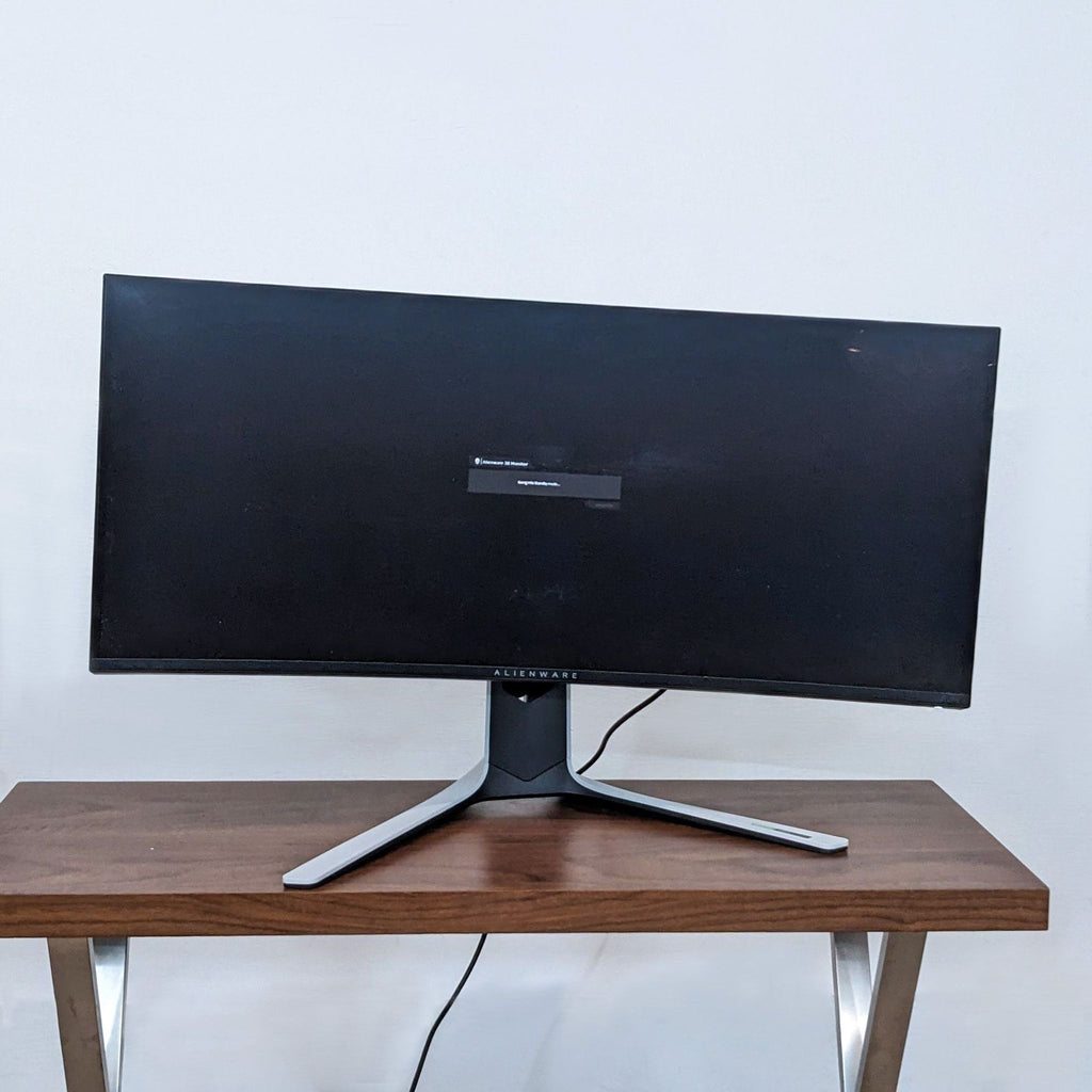 Front view of an Alienware curved monitor on a wooden desk.