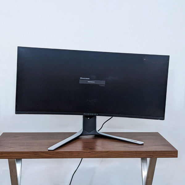 Front view of an Alienware curved monitor on a wooden desk.