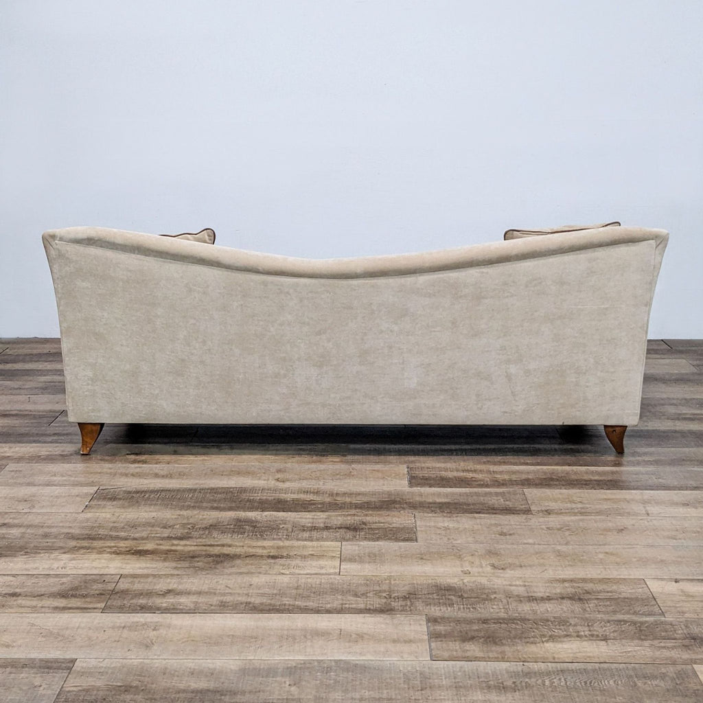 Back view of the curved beige sofa from the Reperch brand with wood feet.