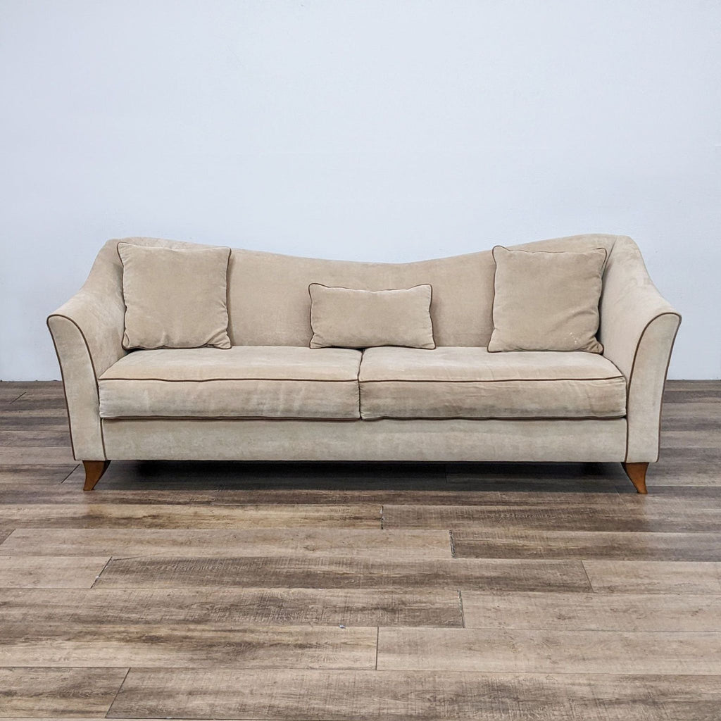 Front view of a beige 3-seat fabric sofa with wood feet and contrasting piping.