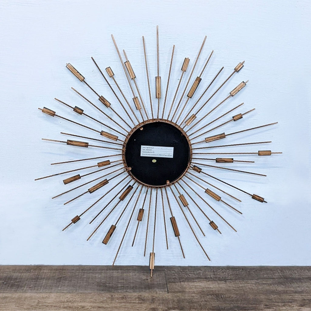 Back of starburst mirror with metal strands extending from black center.
