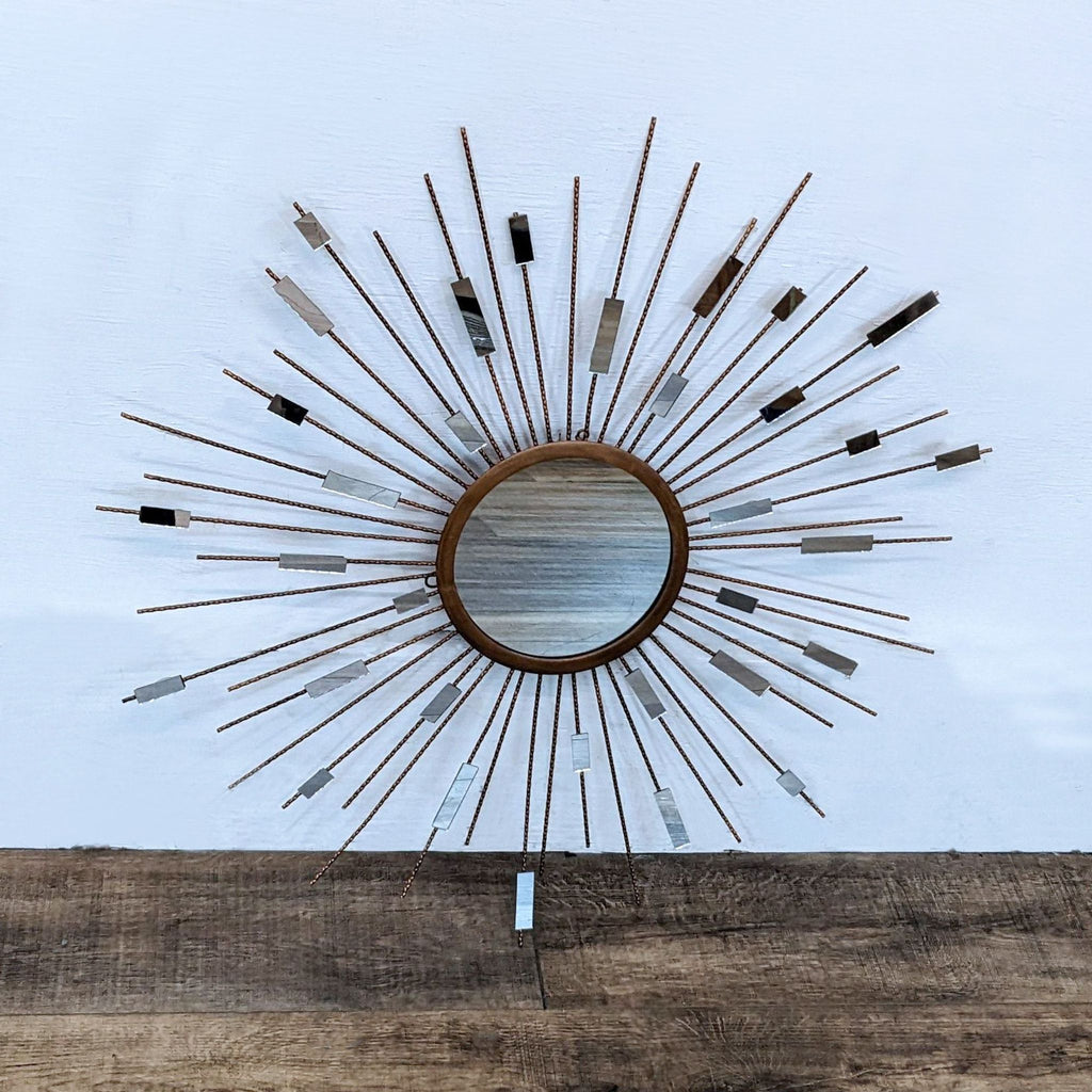 Starburst mirror with metal strands and mirrored pieces radiating from center.