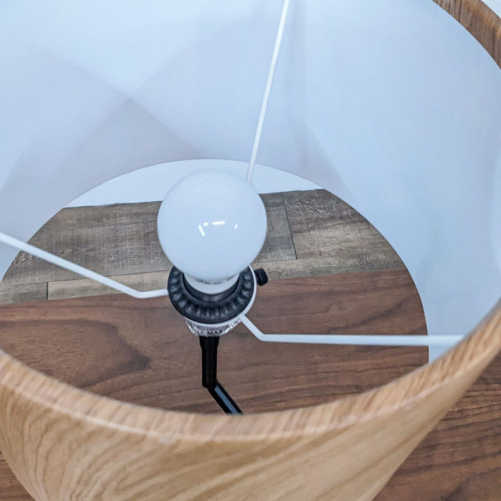 Top view of Reperch lamp, showing the bulb inside a wooden shade with a white interior.