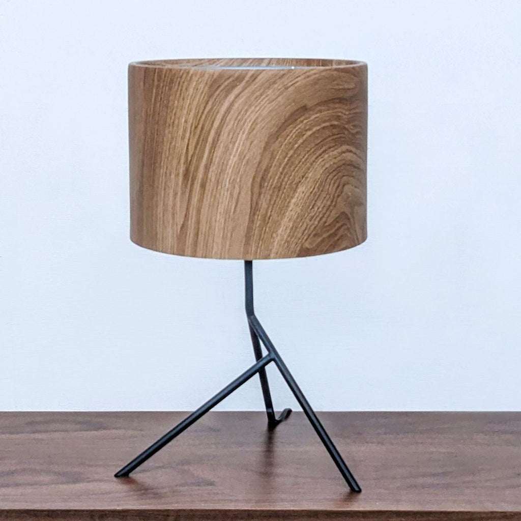 Reperch table lamp with a wooden cylindrical shade and minimalist black metal tripod base.