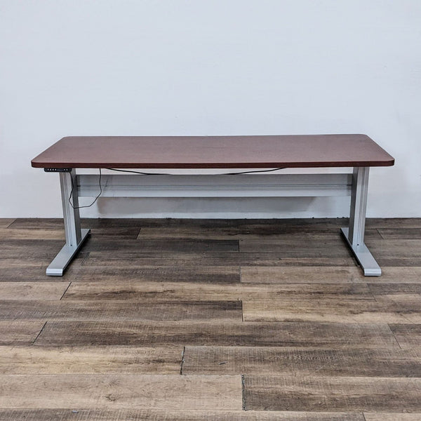 Front view of a Reperch six foot desk with a wood finish look top and gray metal motorized frame.  