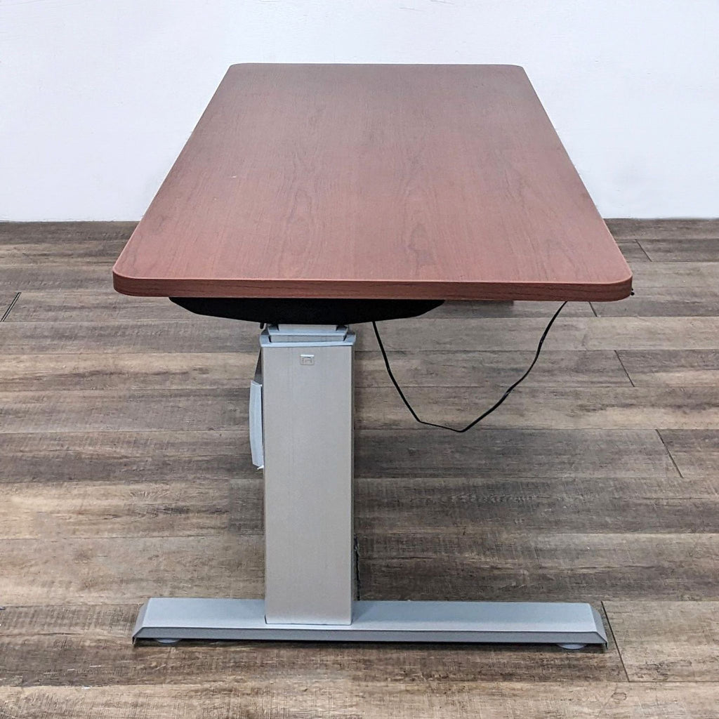 Side view of the Reperch desk, highlighting the wood finish top and sturdy gray metal power-adjustable leg.  