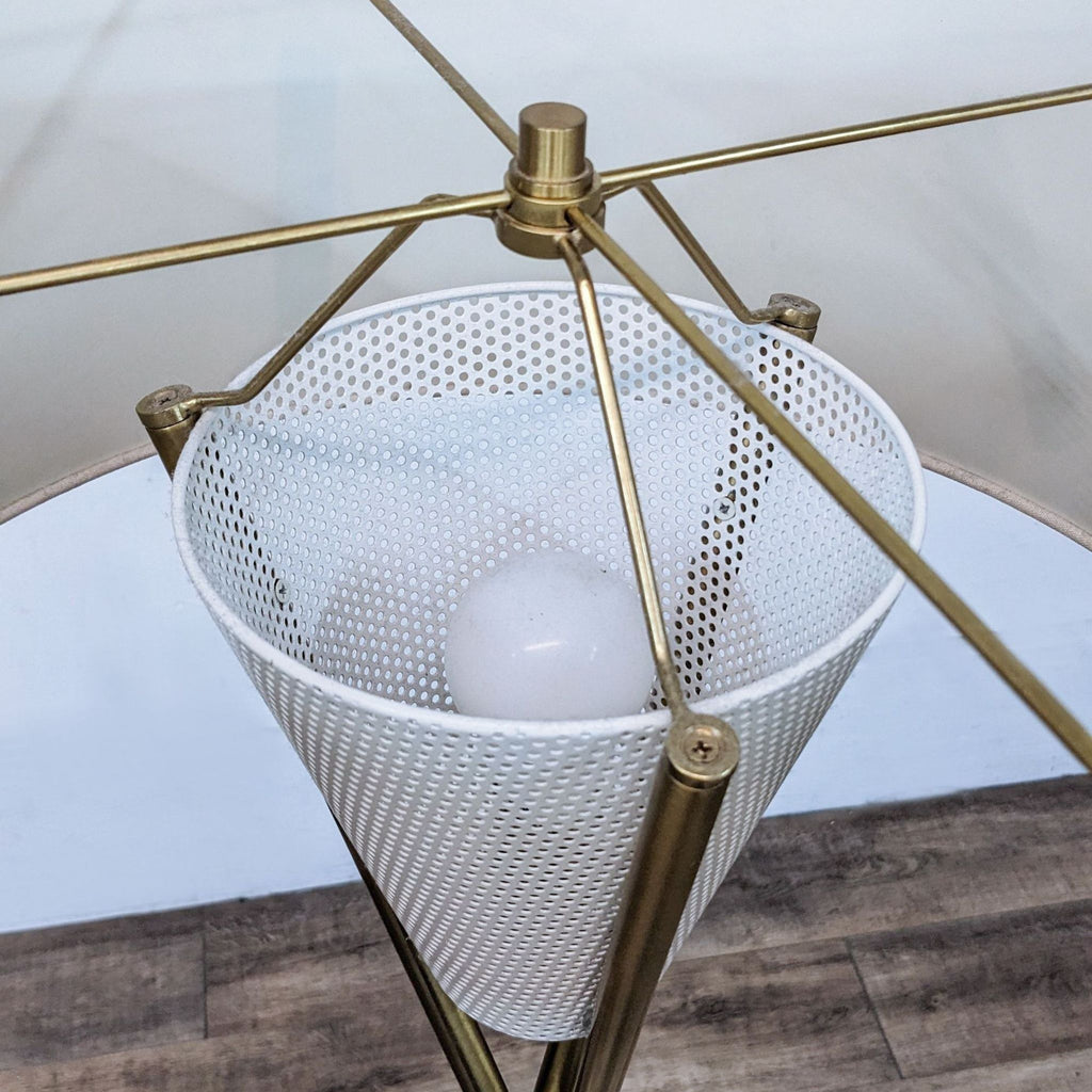 Close-up of lamp bulb inside mesh diffuser with brass supports.