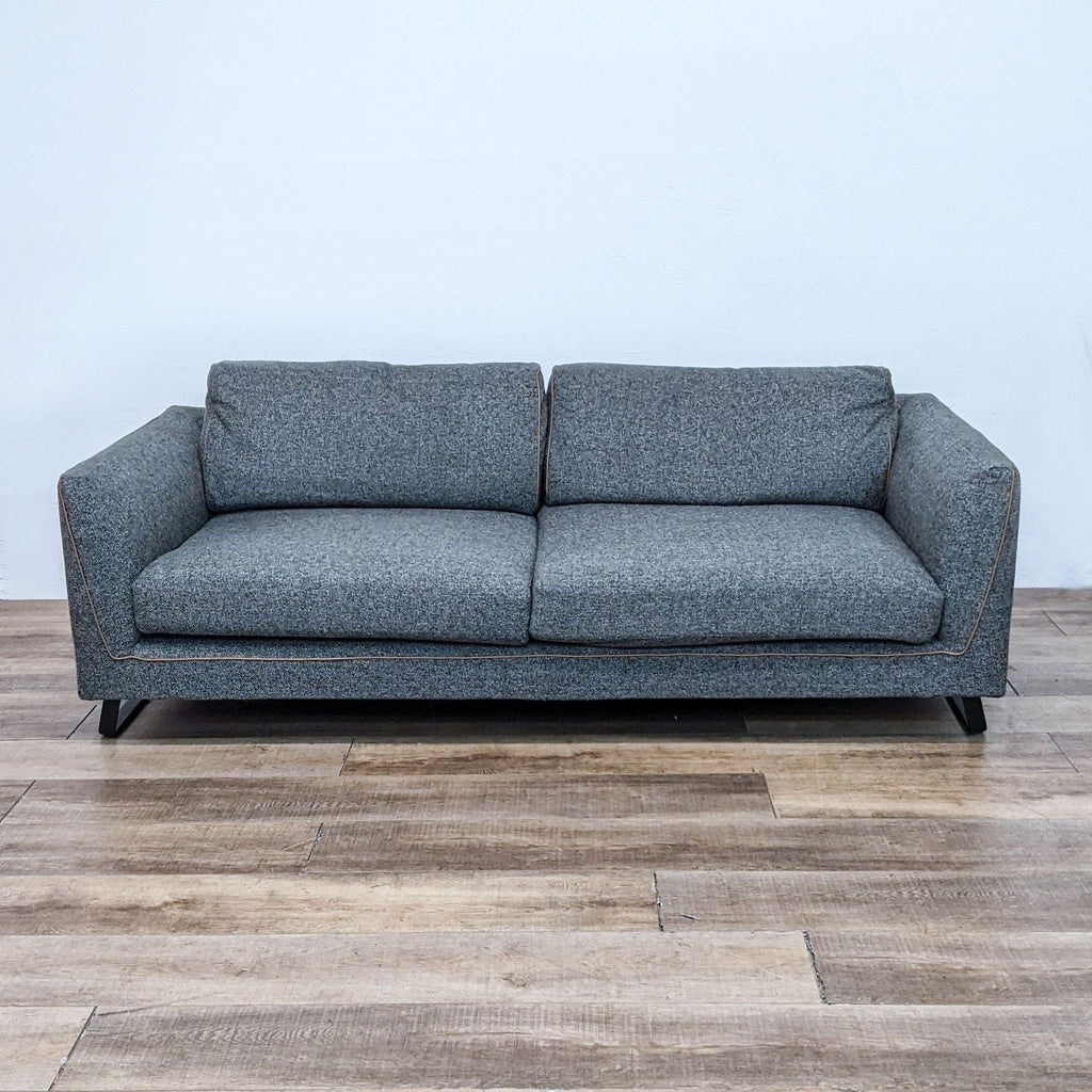 Compact grey sofa with leather edges on a sleek metal frame, perfect for modern interiors.